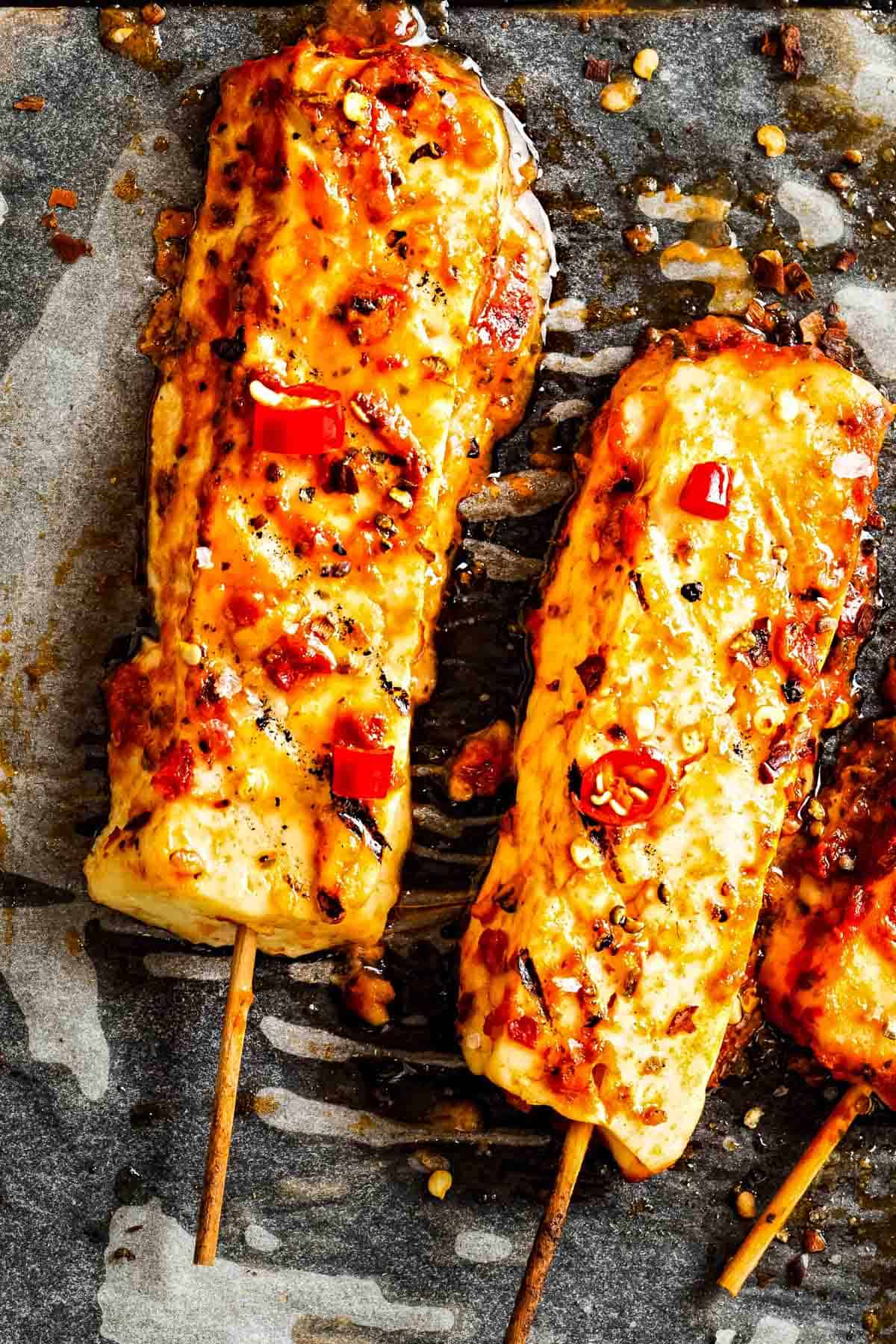 two skewers of hot honey halloumi cheese on parchment paper