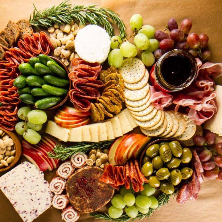 Step 8 of building a $100 Trader Joe's grazing table and the finished board: adding more rosemary marcona almonds to fill in any gaps and adjusting ingredients as needed