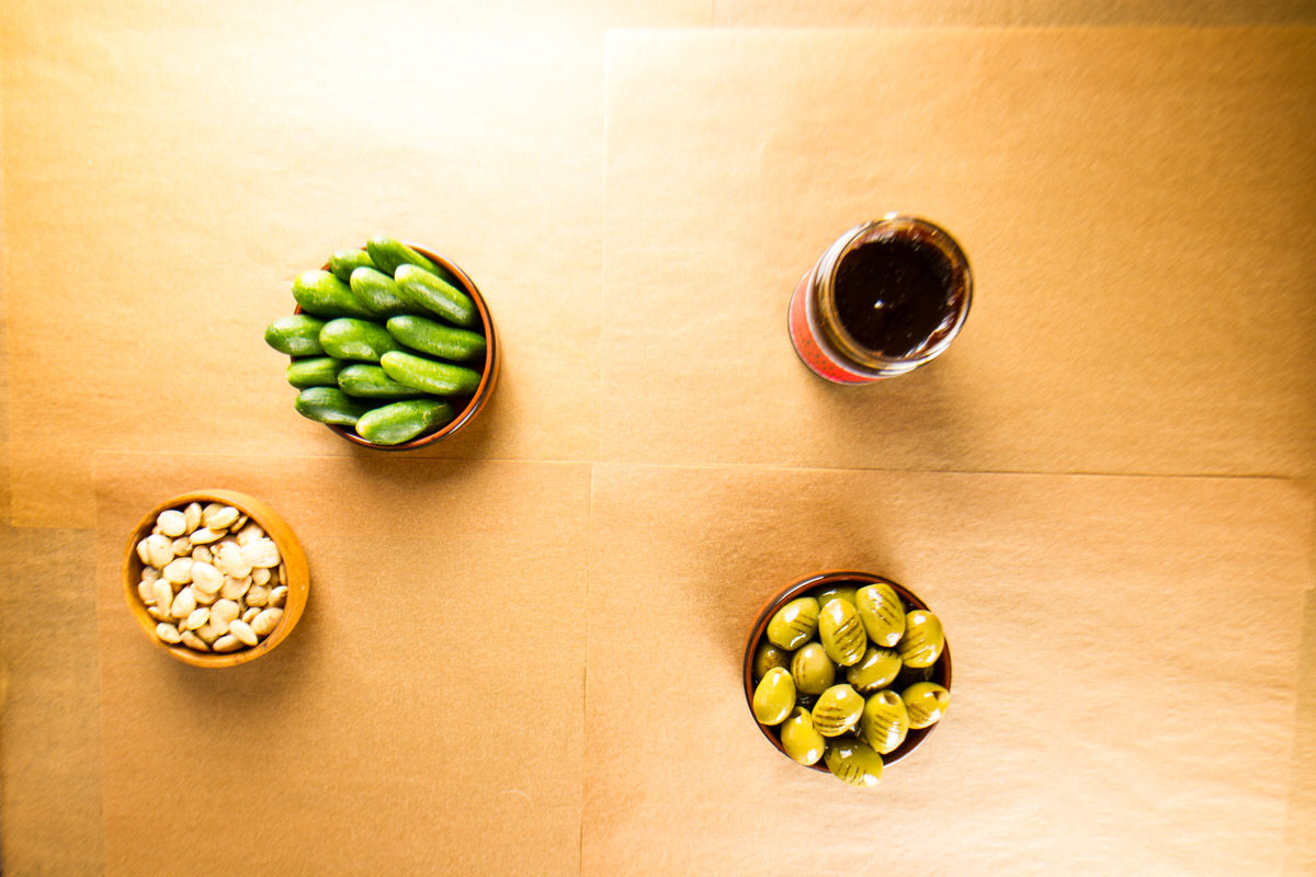 Step one of building a $100 Trader Joe's grazing table: adding bowls of fig butter, teeny tiny cucumbers, rosemary marcona almonds