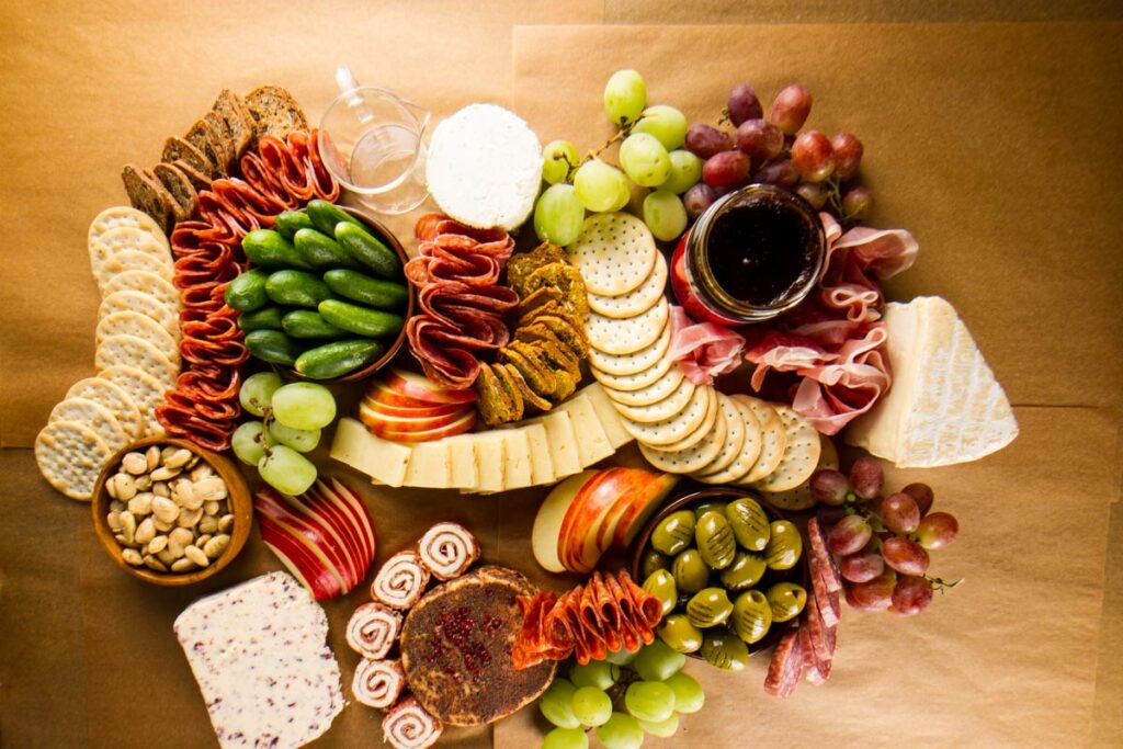 Step six of building a $100 Trader Joe's grazing table: adding small bunches of red and green grapes to the board