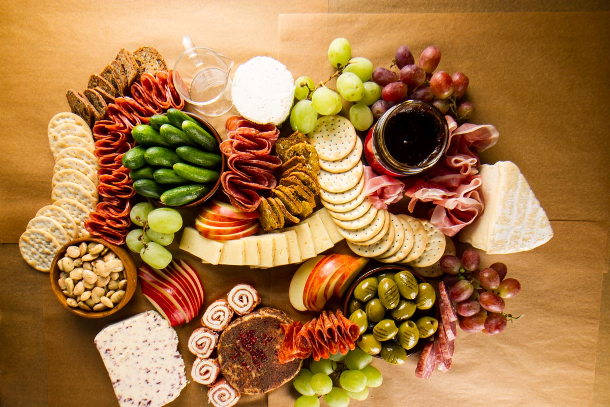 Step six of building a $100 Trader Joe's grazing table: adding small bunches of red and green grapes to the board
