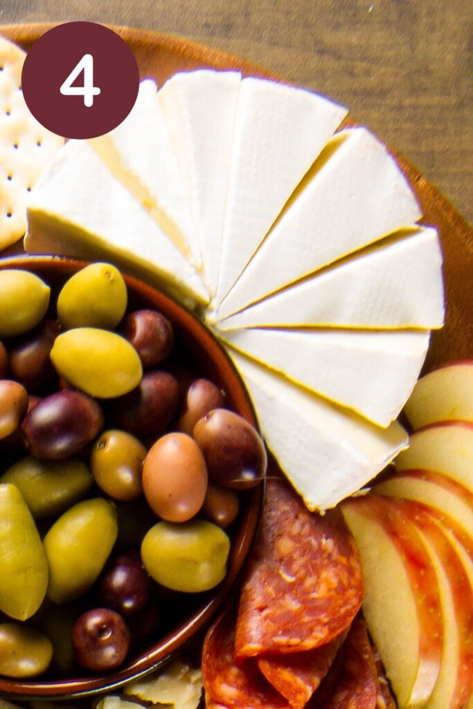 Step four of how to cut Trader Joe's Double Cream Brie: shows 8 wedges arranged on a finished charcuterie board with a round circle and a white #4