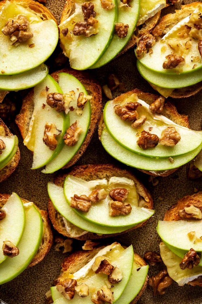 a closeup of apple and brie crostini with walnuts and drizzled with honey